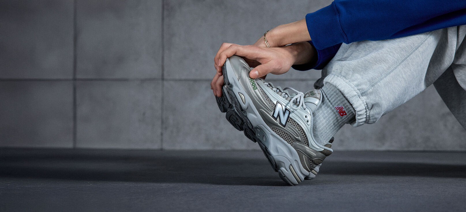 A  knee down shot image of an individual wearing a pair of New Balance 1000 sneakers 